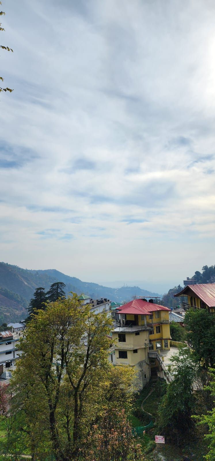 A residential area with houses, a winding road, and a mountainous backdrop.