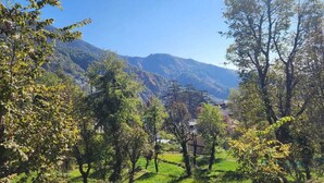 A mountainous landscape with trees and a building in the background. - Hotel Sky pie (Dharamshala)