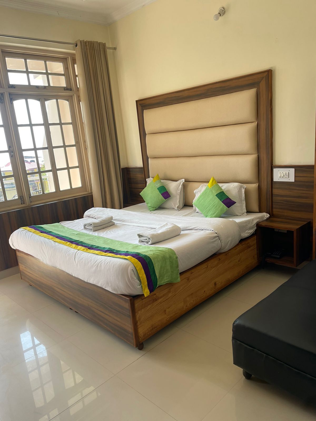 A neatly made bed with a striped blanket, a wooden headboard, and two pillows with colorful designs.