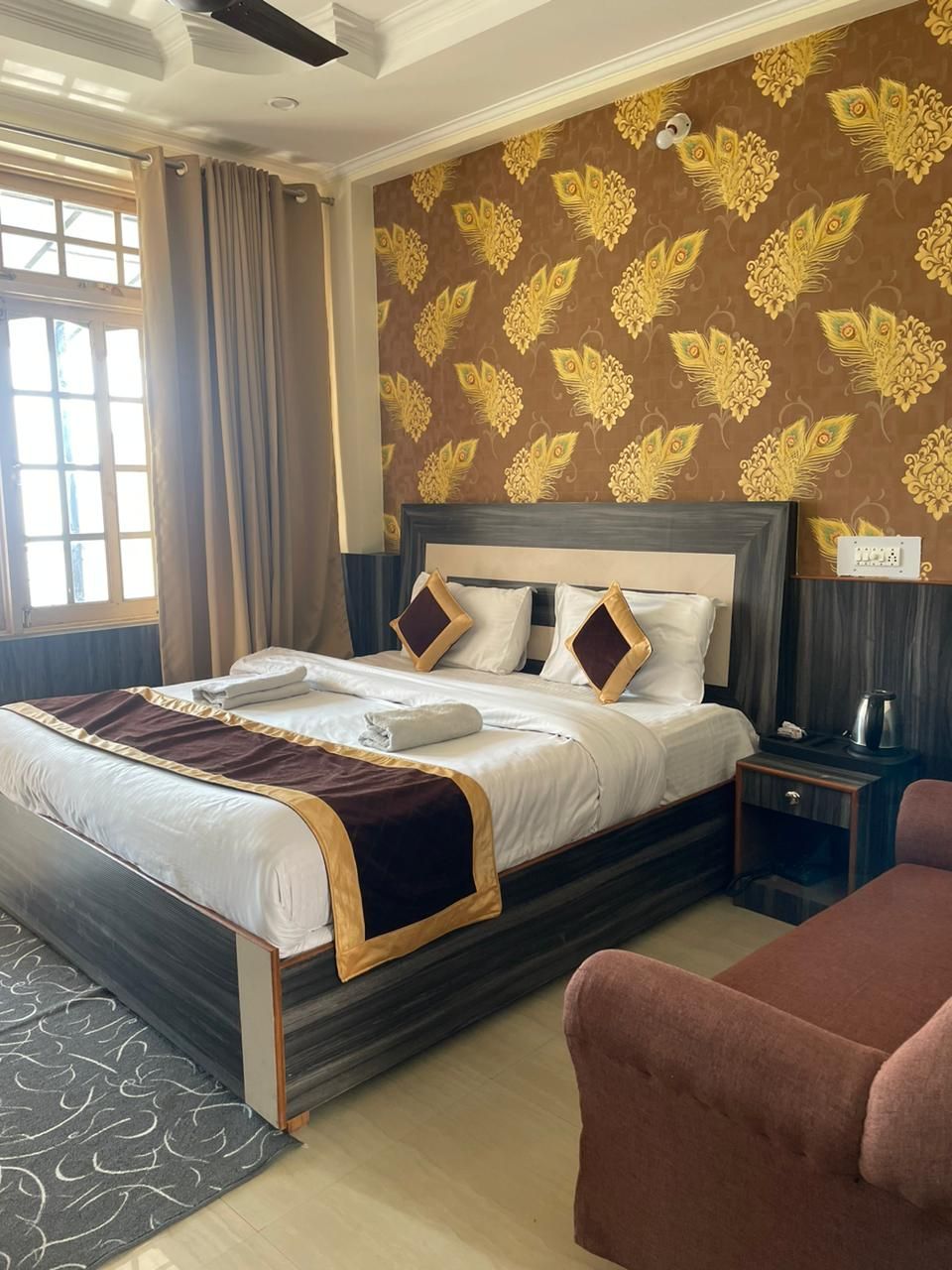 A hotel room with a bed, a nightstand, a chair, and a window with curtains.