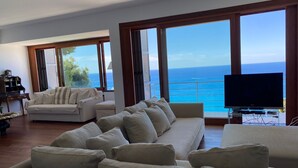 Ein geräumiges Wohnzimmer mit einer großen Couch, einem Fernseher und Blick auf den Ozean.