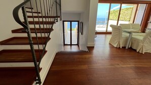 Eine Holztreppe führt zu einem Balkon mit Blick auf den Ozean.