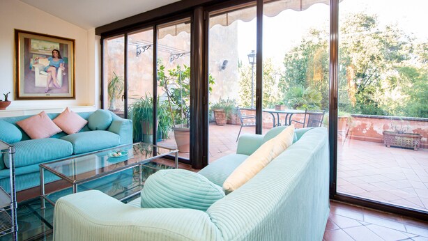 Ein Wohnzimmer mit einer Couch, einem Glastisch und einem Gemälde an der Wand.