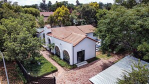 A white building with a tiled roof, arched windows, and a paved courtyard.