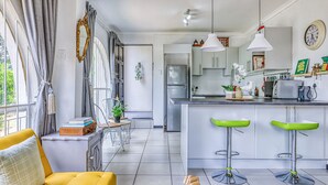 A modern kitchen with a refrigerator, stove, and bar stools.