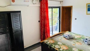 A bedroom with a bed, a wardrobe, a window with red curtains, and an air conditioning unit. - Studio Avec Vue sur Jardin (Mpolongwé)