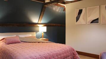 A bedroom with a large bed, a nightstand, a lamp, and two wall-mounted artworks.