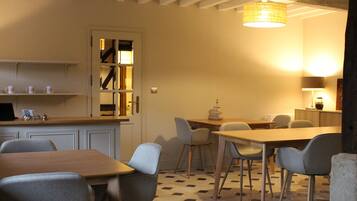 A dining area with a wooden table and chairs, a kitchen with white cabinets and a built-in oven, and a staircase leading to an upper level.