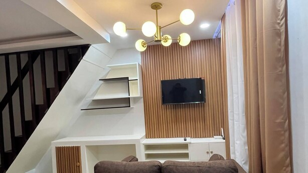 A modern living room with a sofa, TV, and built-in shelves. - PearlDaisy Butuan Transient Home Philippines (Butuan City)