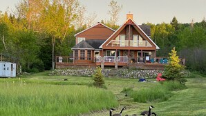 A house with a deck and a grassy yard. - 5 Bedroom Waterfront Lake House  (Bonfield)