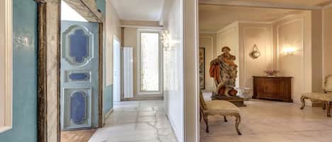 A hallway with a statue, a chair, and a cabinet.