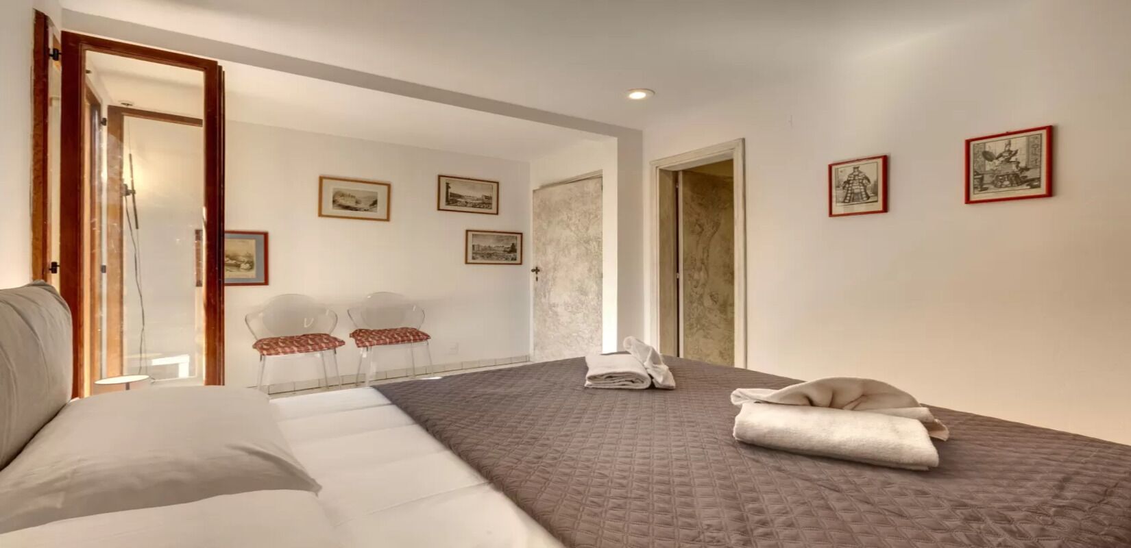 Ein Hotelzimmer mit einem Bett, einer Couch, einem Sessel und einem kleinen Tisch. An der Wand hängen gerahmte Bilder.