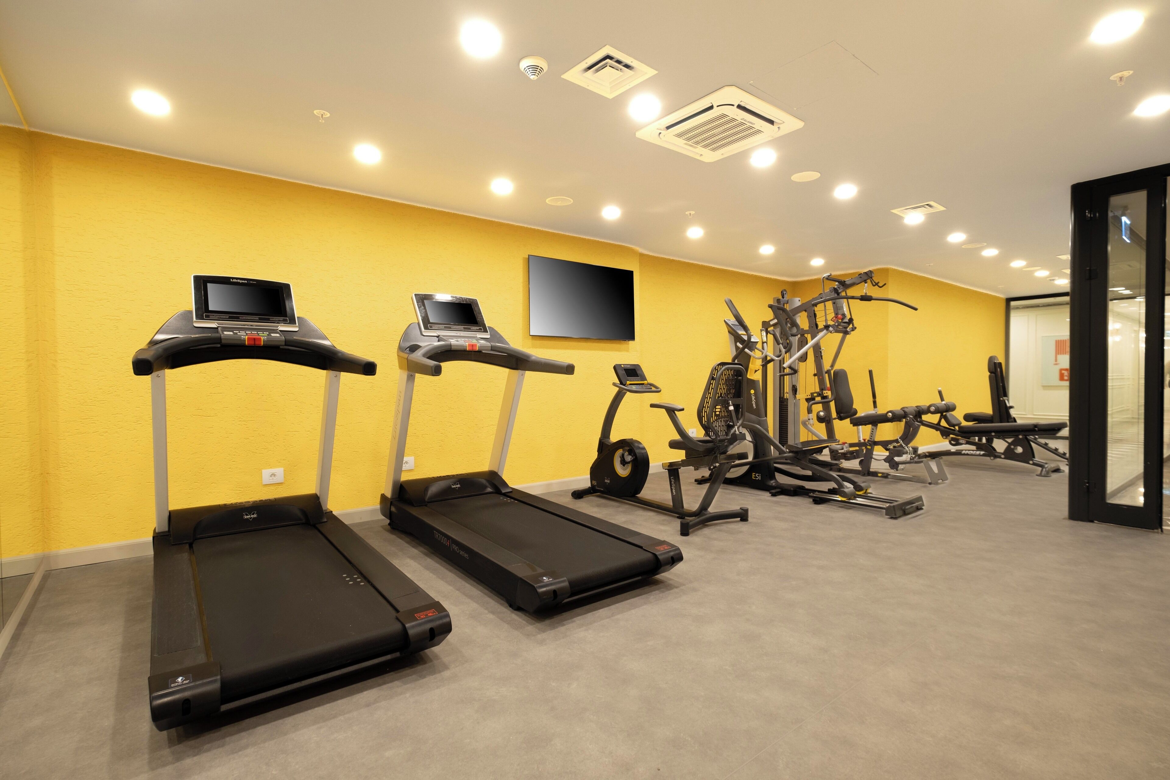 Une salle de sport équipée de tapis de course, de vélos elliptiques et de matériel de musculation.