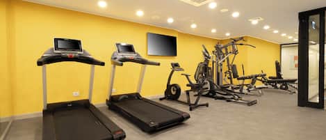 Une salle de sport équipée de tapis de course, de vélos elliptiques et de matériel de musculation.