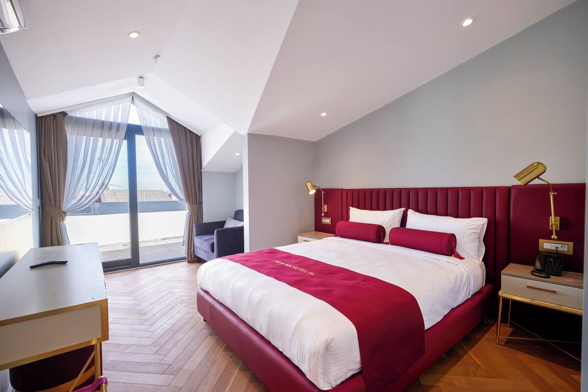 A modern hotel room with a large bed, a desk, and a chair.