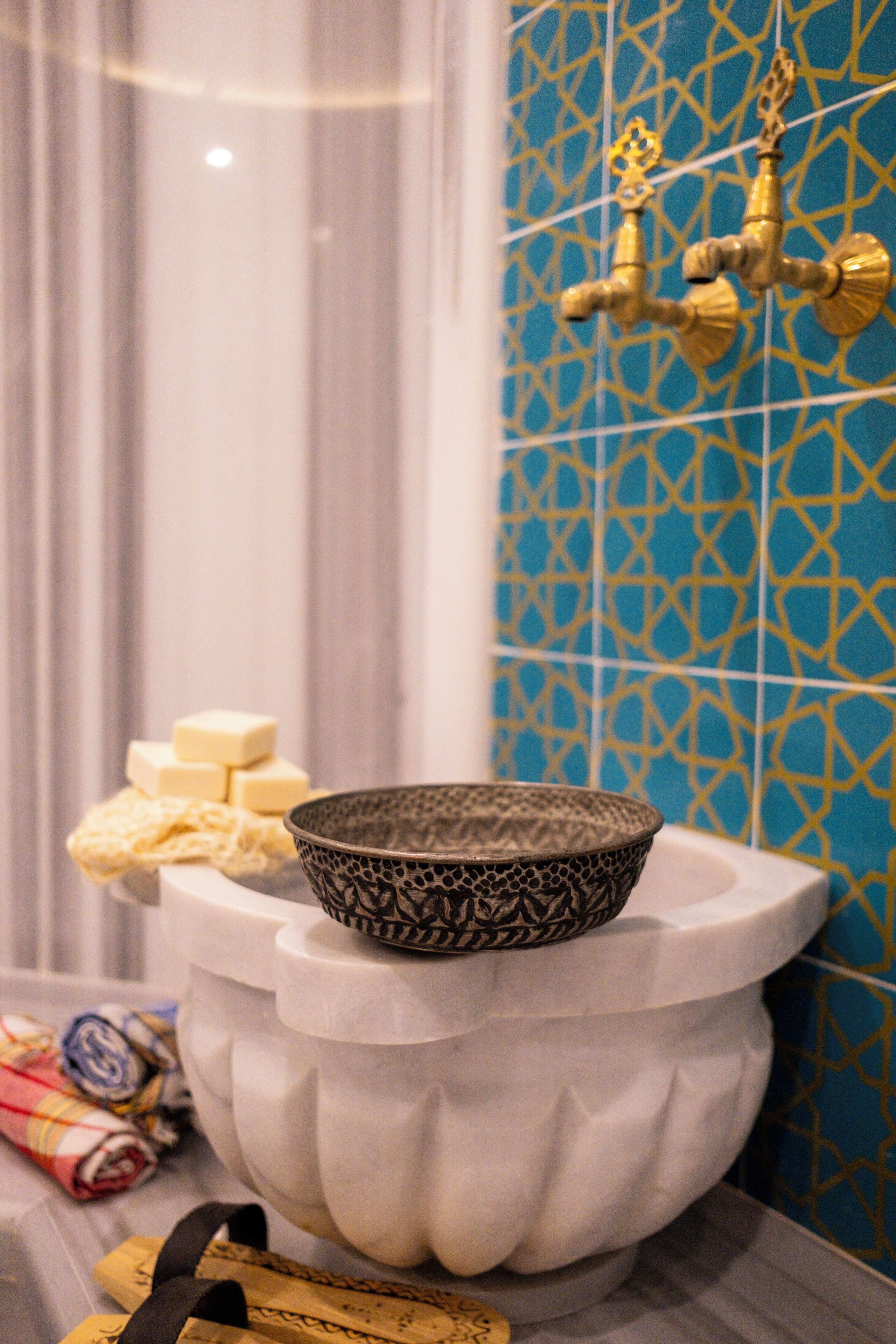 A bathroom with a decorative sink, a gold faucet, and patterned tiles.