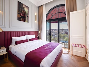 A hotel room with a large bed, a city view, a painting on the wall, and a window with curtains. - New Inn Hotel Old Town (Istanbul)