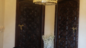 A room with a chandelier, two black chairs, and a wooden door with intricate carvings. - Eden Palm Resident Marrakech (Marrakech)