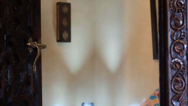 A bedroom with a bed, a nightstand, a lamp, and a decorative wall hanging. - Eden Palm Resident Marrakech (Marrakech)