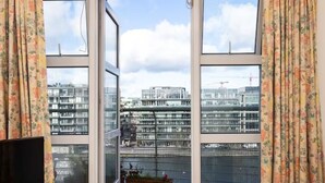Ein Zimmer mit großen Fenstern und Blick auf moderne Gebäude sowie einen Baukran.