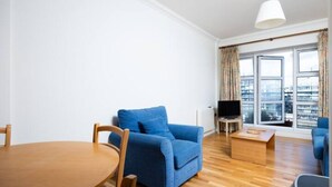 Ein modernes Wohnzimmer mit einem blauen Sofa, einem Holztisch und einem Fernseher.