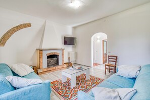 A living room with a fireplace, blue sofas, a coffee table, and a patterned rug.