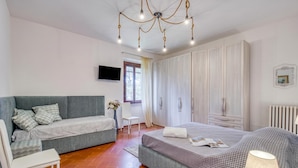 A bedroom with a bed, a sofa, a chair, a TV, and a wardrobe. - La Casa Della Quercia Relax In Tuscany (Montaione)