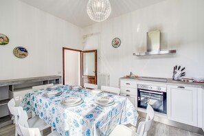 A compact kitchen with a dining area, white cabinetry, a built-in oven, and a chandelier.
