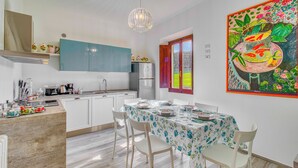 Une cuisine moderne avec des meubles blancs, un réfrigérateur en acier inoxydable et un coin repas avec une table dressée pour deux personnes.