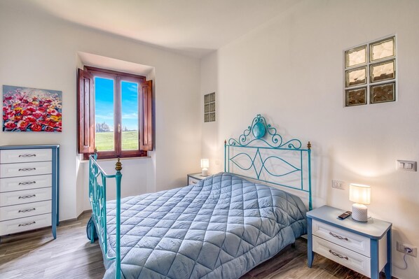 A bedroom with a bed, a nightstand, a dresser, a window, and a painting.
