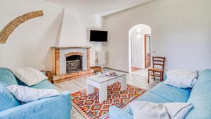 Un salon avec une cheminée, deux canapés, une table basse et un téléviseur fixé au mur.