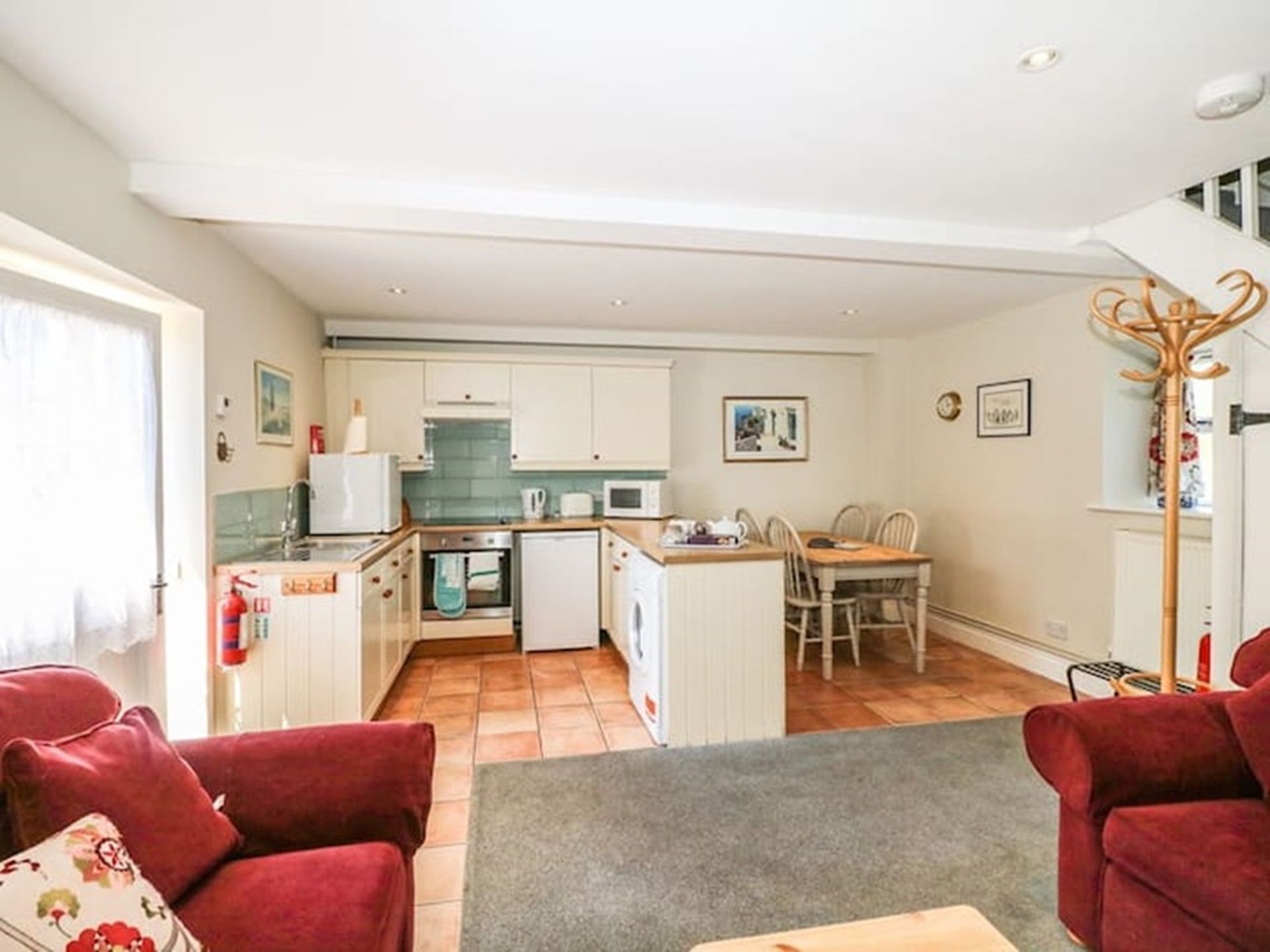 A compact living space with a kitchenette, a dining area, and a seating area with red sofas.