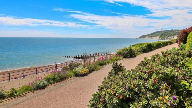 A coastal walkway with a paved path, a railing, and a view of the sea and distant hills. - Escape to Luxury Stylish Apartment in Eastbourne (Eastbourne)