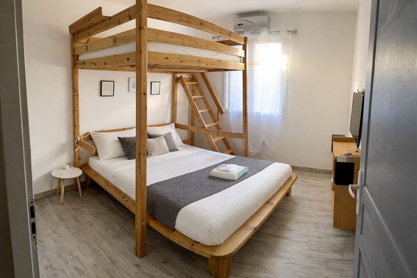A bunk bed with a ladder, a small bedside table, and a television on a cabinet.