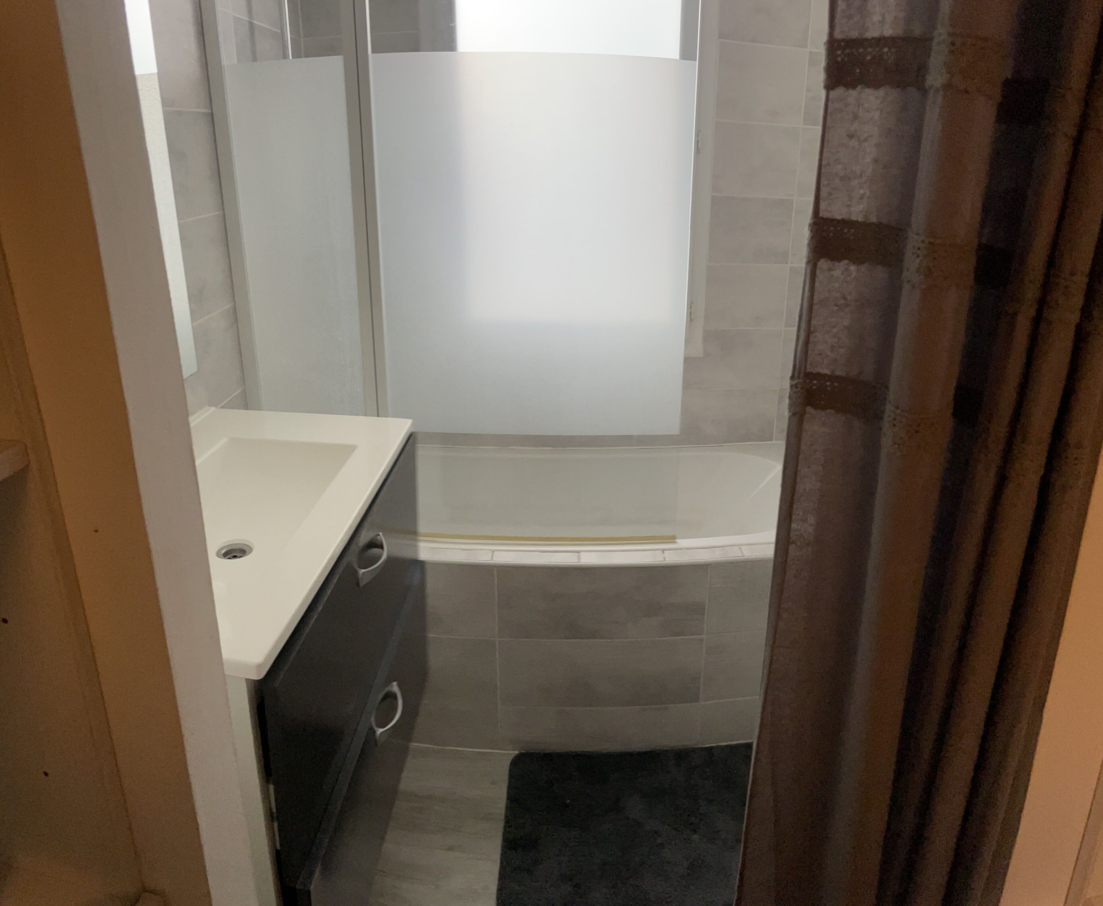 Une salle de bain avec un lavabo blanc, une baignoire et un espace douche.