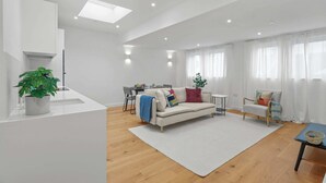 A modern living room with a sofa, armchairs, a dining table, and a kitchen area. - City Escape with a Touch of Class (Eastbourne)