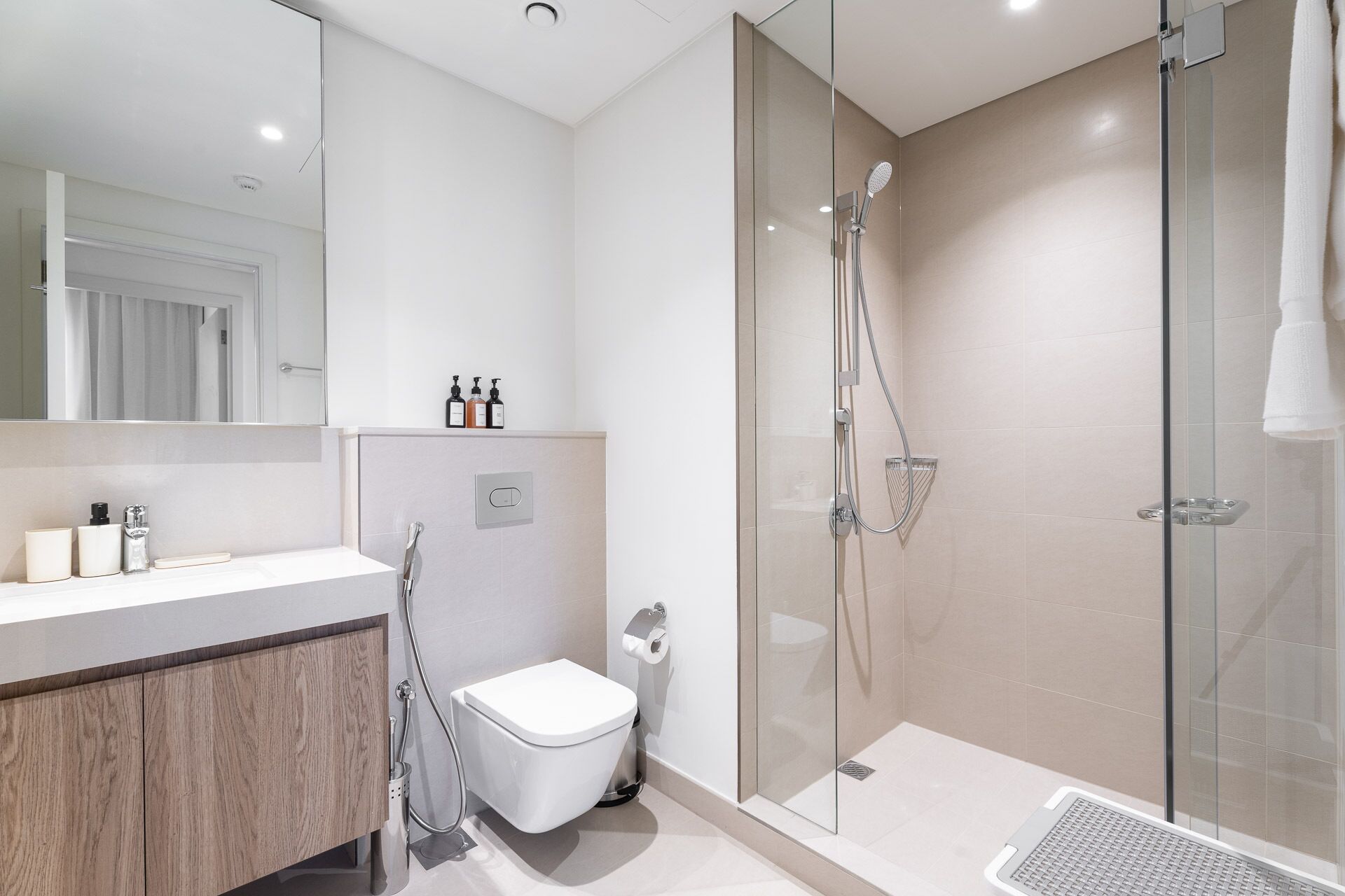 A modern bathroom with a glass shower enclosure, a toilet, and a vanity with a mirror.