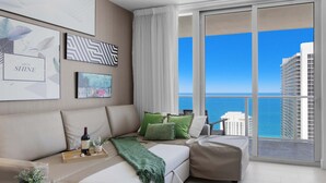 A modern living room with a sofa, a coffee table, and a view of the ocean. - Endless Views | Oceanfront Balcony | Hot Tub (Hollywood)