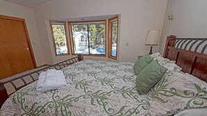 Une chambre avec un grand lit, une fenêtre donnant sur un beau paysage, une table de chevet et une lampe.