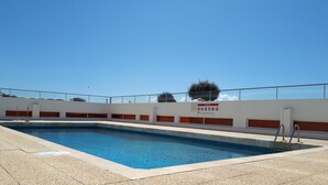 A swimming pool with a tiled deck, a safety sign, and a clear blue sky.