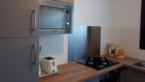 A compact kitchen with a microwave, toaster, and gas stove.