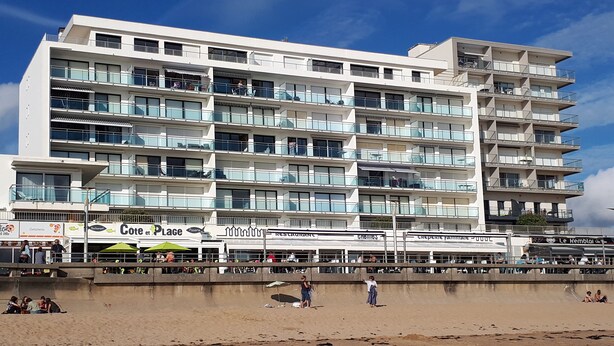 A multi-story hotel with balconies and a beachside location.