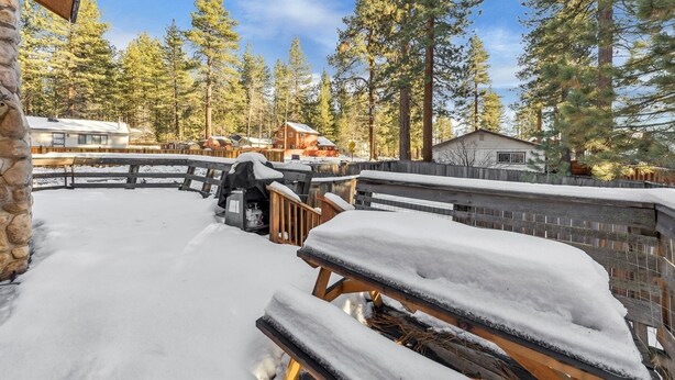 A snow-covered outdoor area with a barbecue grill, wooden benches, and a stone wall. - 750 Stanford Avenue 3 Bedroom Cabin by RedAwning (South Lake Tahoe)