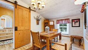 A wooden dining area with a table, chairs, and a chandelier. - Pinecone Haven - Where Northwoods meets the Southwest  (Sturgeon Bay)