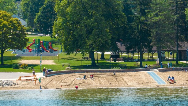 A park with a playground, sandy beach, and a body of water. - Pinecone Haven - Where Northwoods meets the Southwest  (Sturgeon Bay)