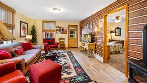A cozy living room with a sofa, chairs, a fireplace, and a wooden wall. - Pinecone Haven - Where Northwoods meets the Southwest  (Sturgeon Bay)