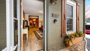 A house entrance with a wooden door, a number '406' sign, a window with brown shutters, and a planter with plants on the porch. - Pinecone Haven - Where Northwoods meets the Southwest  (Sturgeon Bay)