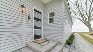 A house with a front porch, a door, and a small window. - Bright Houghton Lake Home w/ Boat Dock + Fire Pit (Houghton Lake)
