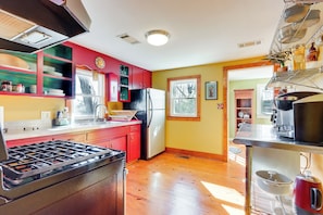 A kitchen with a gas stove, refrigerator, and wooden floors.