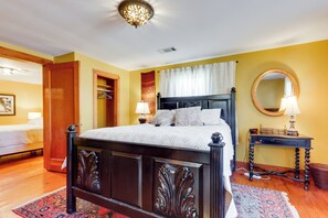 A bedroom with a wooden bed, a bedside table with a lamp, a mirror, and a wardrobe. - 2 Mi to UA: Central Fayetteville Home w/ Patios (Fayetteville)
